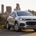 A silver 2021 Chevy Trax is parked in front of a city skyline.