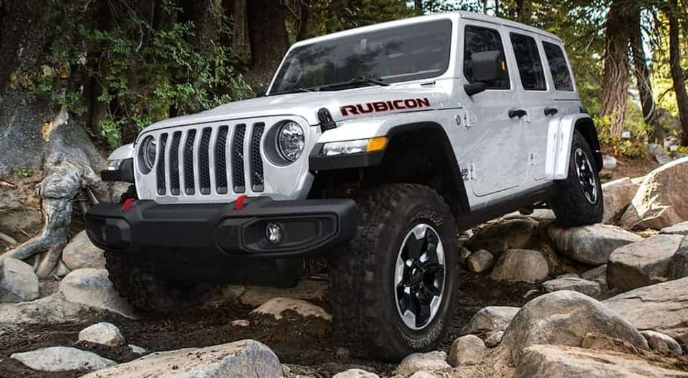A white 2020 Jeep Wrangler Unlimited Rubicon is off-roading on a rocky trail.