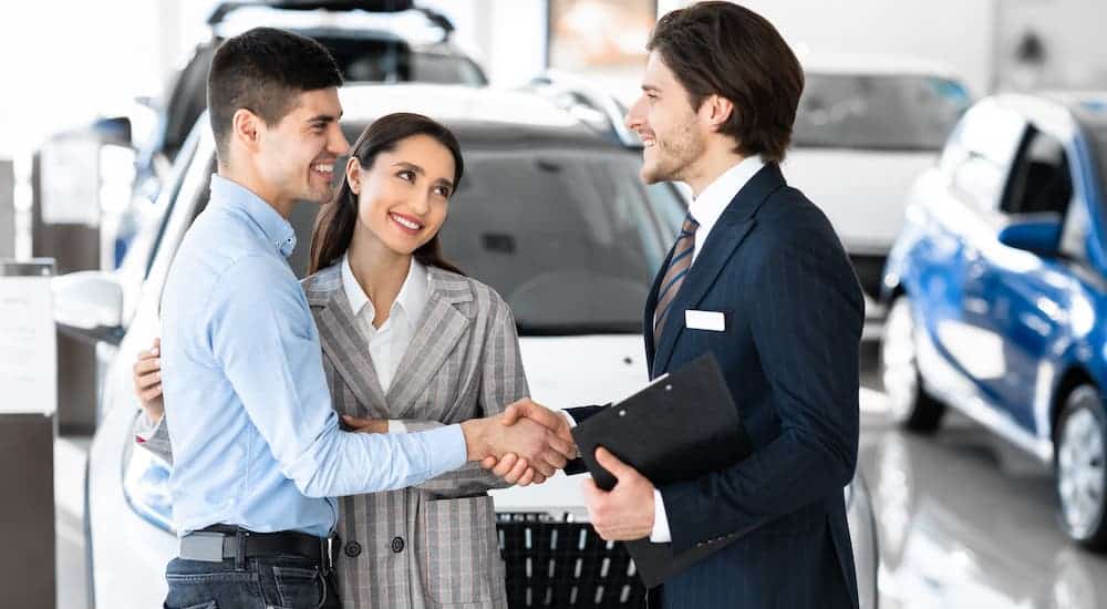 Two men are shaking hands after a car purchase.