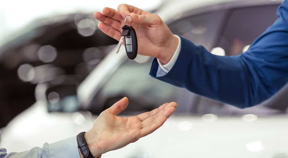 A close up of a set of car keys being exchanged by two hands.
