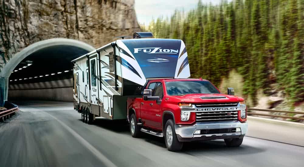 A red 2020 Chevy Silverado 2500HD is towing a camper out of a tunnel.