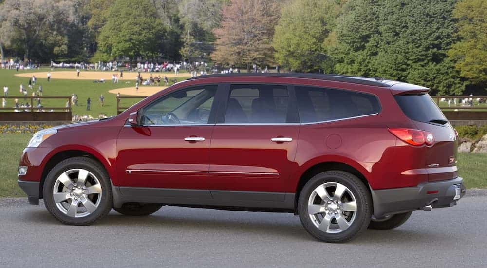 A red 2009 used Chevy Traverse is parked at a baseball field after leaving a used car dealer.