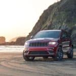 A red 2020 Jeep Grand Cherokee is parked on the beach after leaving a Jeep dealership near you.