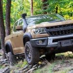 A tan 2021 Chevrolet Colorado ZR2 Bison is driving through the woods.