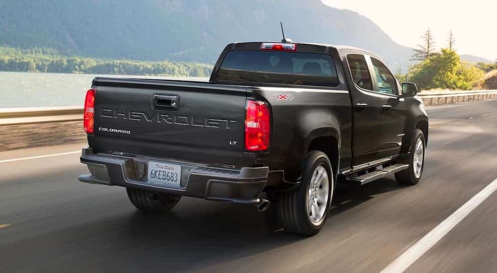 A black 2021 Chevrolet Colorado is driving down the road with mountains in the background.
