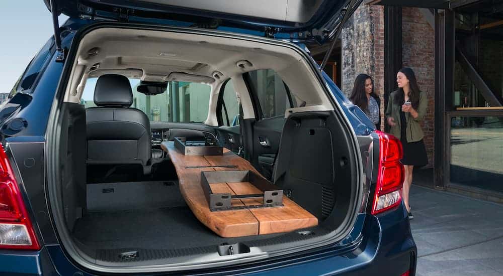 A blue 2021 Chevrolet Trax has its hatch open with a large piece of wood loaded in it showing the cargo space of Chevy SUVs.