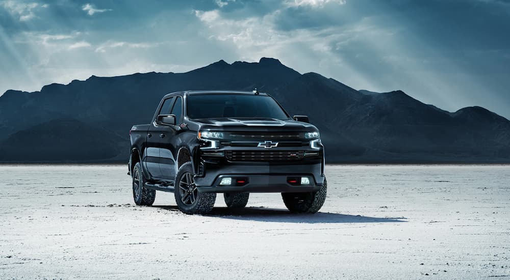 A black 2021 Chevy Silverado 1500 Trailboss Midnight Edition is parked with mountains in the background.