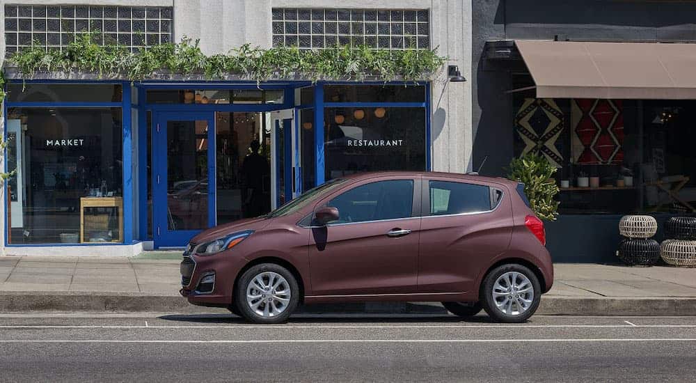 A burgundy 2021 Chevy Spark is parked in front of a market.