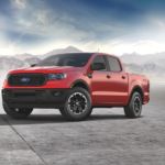 A red 2021 Ford Ranger STX is parked on the concrete with misty mountains in the background.