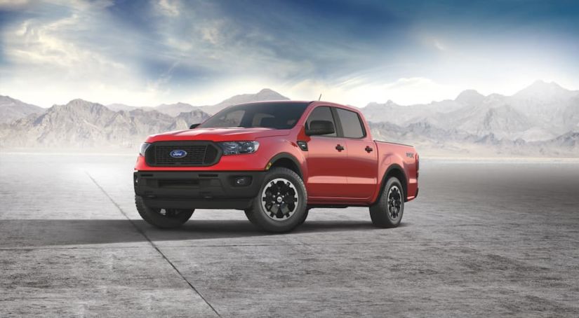 A red 2021 Ford Ranger STX is parked on the concrete with misty mountains in the background.