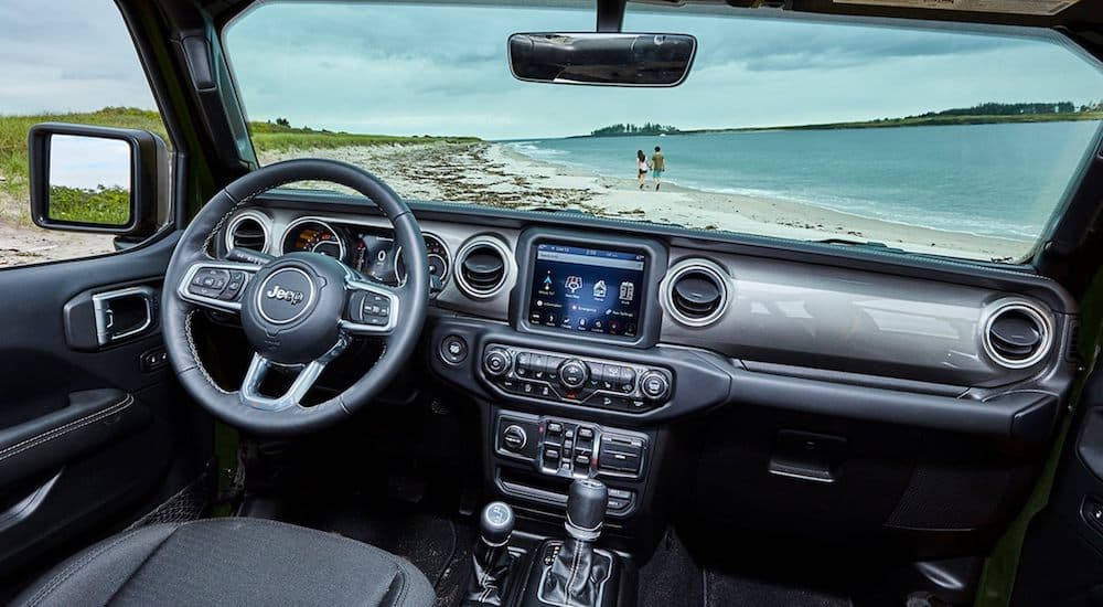 The black and silver interior of a 2021 Jeep Wrangler is shown overlooking the beach.