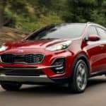 A red 2021 Kia Sportage is driving down the road.