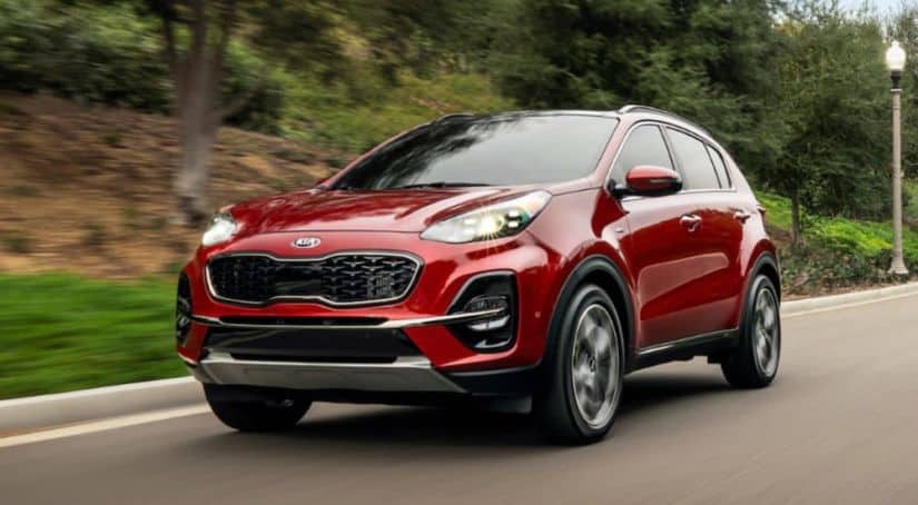 A red 2021 Kia Sportage is driving down the road.