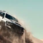A silver 2021 Ram 1500 TRX is sliding down a desert hill kicking up dust, showing you what Ram trucks are all about.