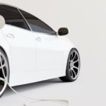 A white electric car is shown from the side while charging.