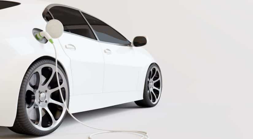 A white electric car is shown from the side while charging.