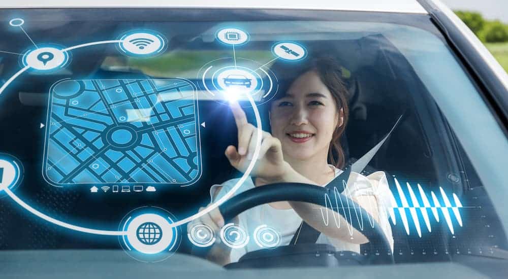 A woman is making selections on a holographic heads up display while driving.