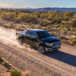 A black 2019 used Ram 1500 is driving down a dirt road kicking up some dust.