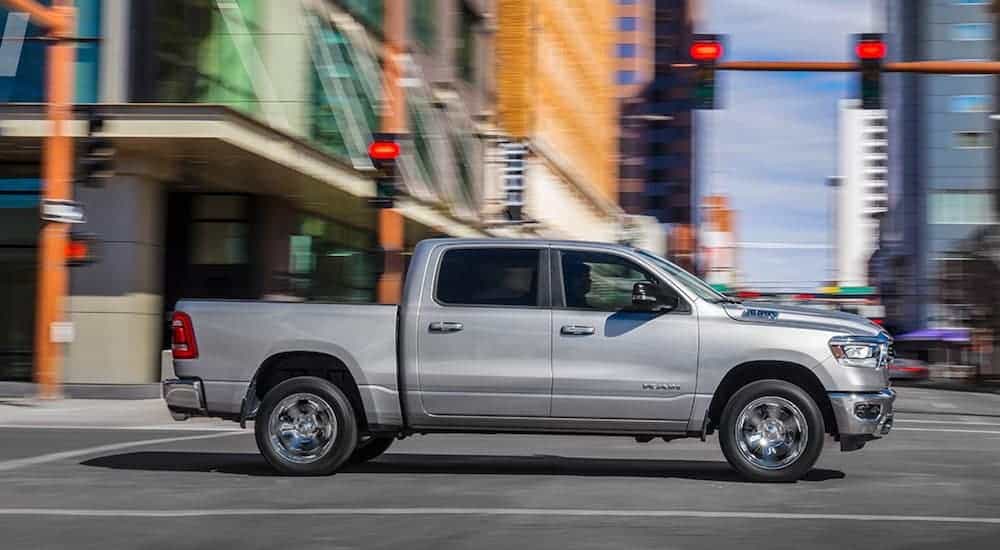 A silver 2019 used Ram 1500 is driving through the city.