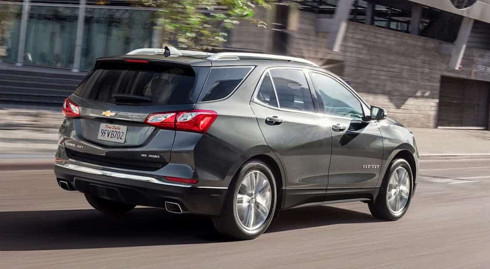 A grey 2020 Chevy Equinox is driving down a city street.
