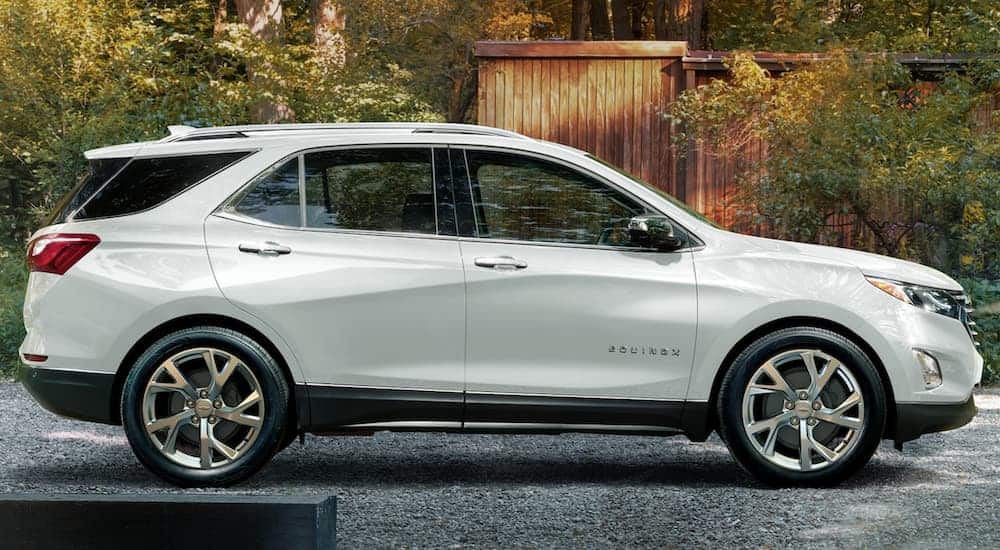 A white 2020 Chevy Equinox is shown from the side in front of a modern house.