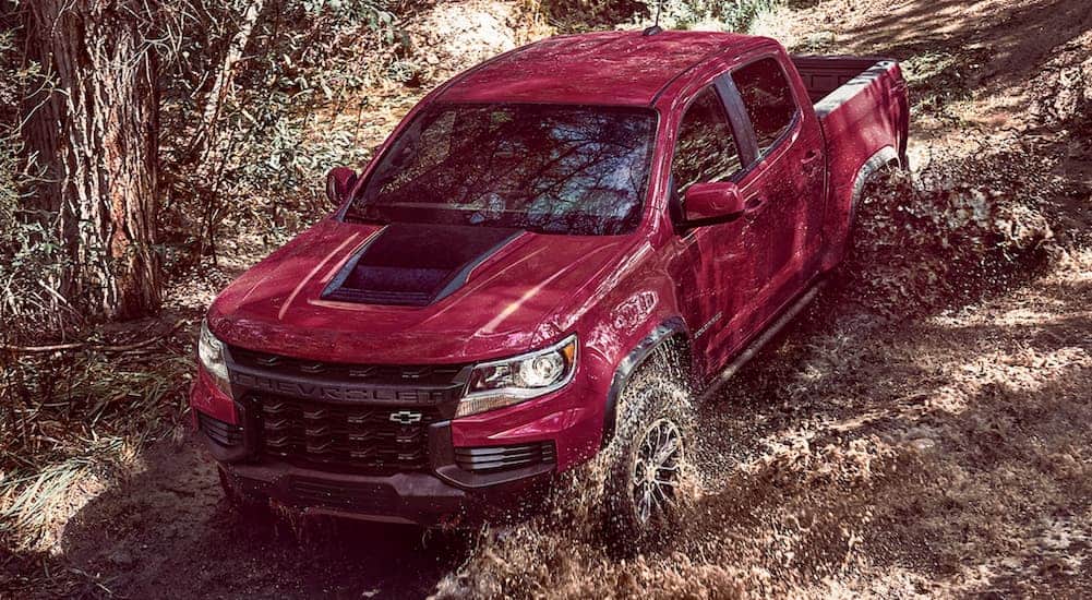 A red 2021 Chevy Colorado ZR2 is off-roading in the mud after winning the 2021 Chevy Colorado vs 2021 Jeep Gladiator comparison.