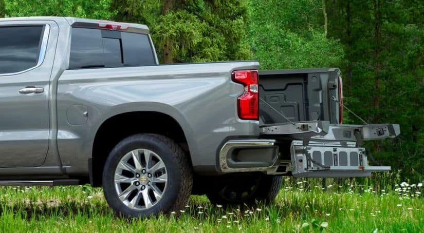 A silver 2021 Chevy Silverado 1500 is shown from the side with its Multi-Flex Tailgate open.