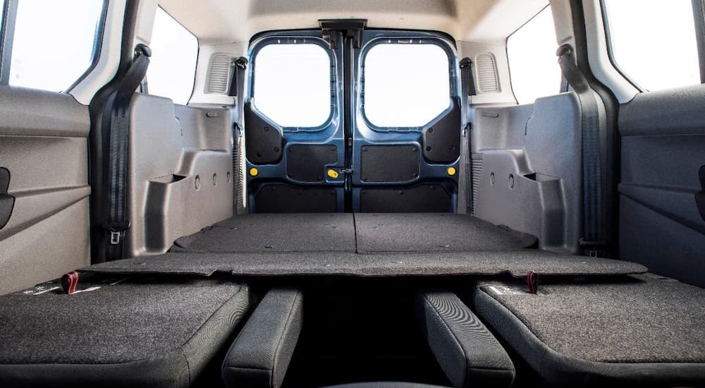 The seats are folded down in the back of a 2021 Ford Transit Connect and shown from the front of the vehicle.
