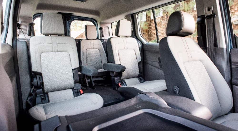 The multiple rows of gray seats are shown in a popular 2021 Ford commercial vehicle, a Ford Transit Connect.