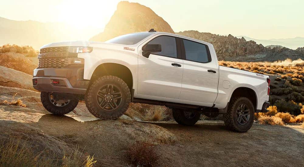 A white 2021 Chevy Silverado 1500 Z71 is shown from the side parked in the desert with rock formations in the background.