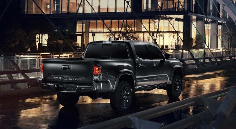 A black 2021 Toyota Tacoma Nightshade Edition is shown from behind driving down a bridge at night.
