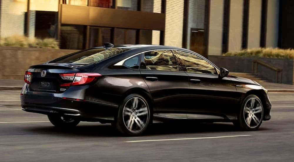 A black 2021 Honda Accord is driving on a city street after winning the 2021 Honda Accord vs 2021 Nissan Altima comparison.