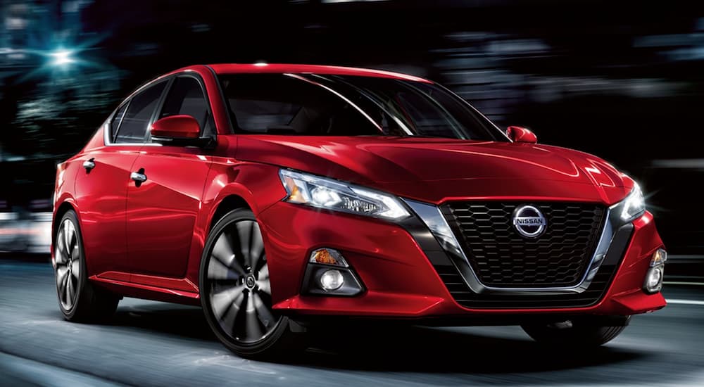 A red 2021 Nissan Altima is on a city street at night.