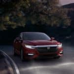 A red 2021 Honda Insight Touring is driving down the road at night with its headlights on.