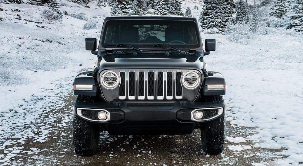 A black 2021 Jeep Wrangler is shown from the front parked in the snow.