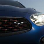 A close up of the front driver side headlight and grille on a blue 2021 Kia Forte GT.
