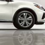 A closeup shows the wheel on a white 2021 Nissan Murano and it's reflection on a shiny floor.