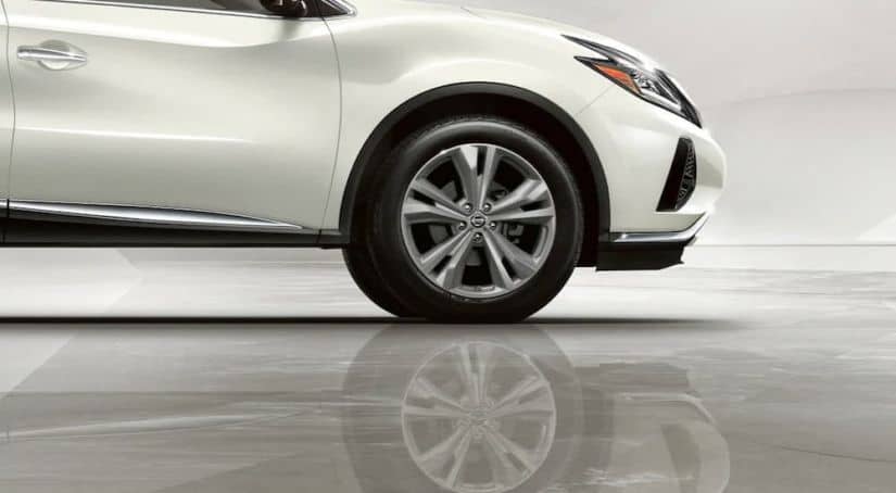 A closeup shows the wheel on a white 2021 Nissan Murano and it's reflection on a shiny floor.