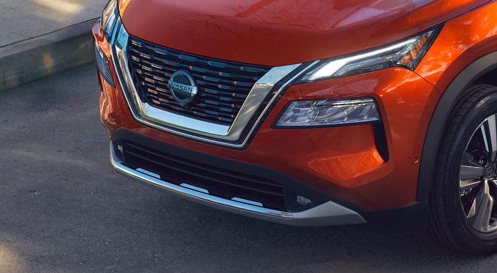 A close up is shown from as a high angle of the front grille on an orange 2021 Nissan Rogue.