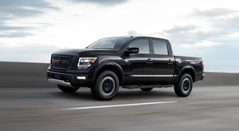 A black 2021 Nissan Titan is driving on a highway.