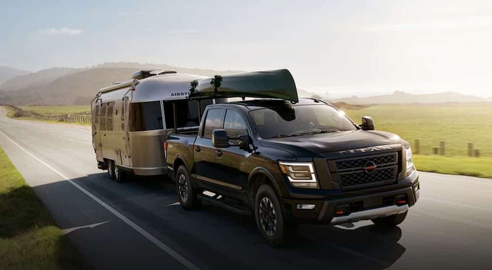 A black 2021 Nissan Titan with a canoe on the roof is towing an Airstream.