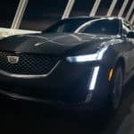 A black 2021 Cadillac CT5-V is driving over a bridge at night.