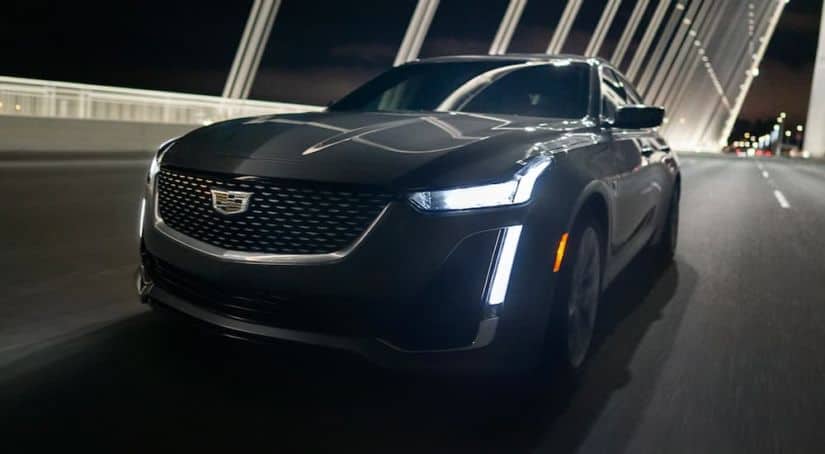 A black 2021 Cadillac CT5-V is driving over a bridge at night.