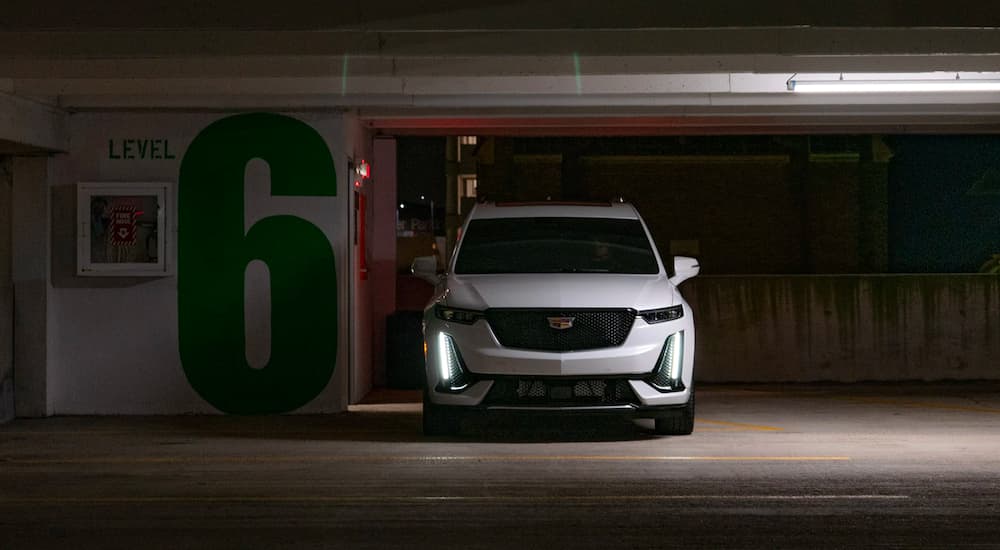 A popular Cadillac lease deal, a white 2021 Cadillac XT6, is shown from the front in a parking garage.