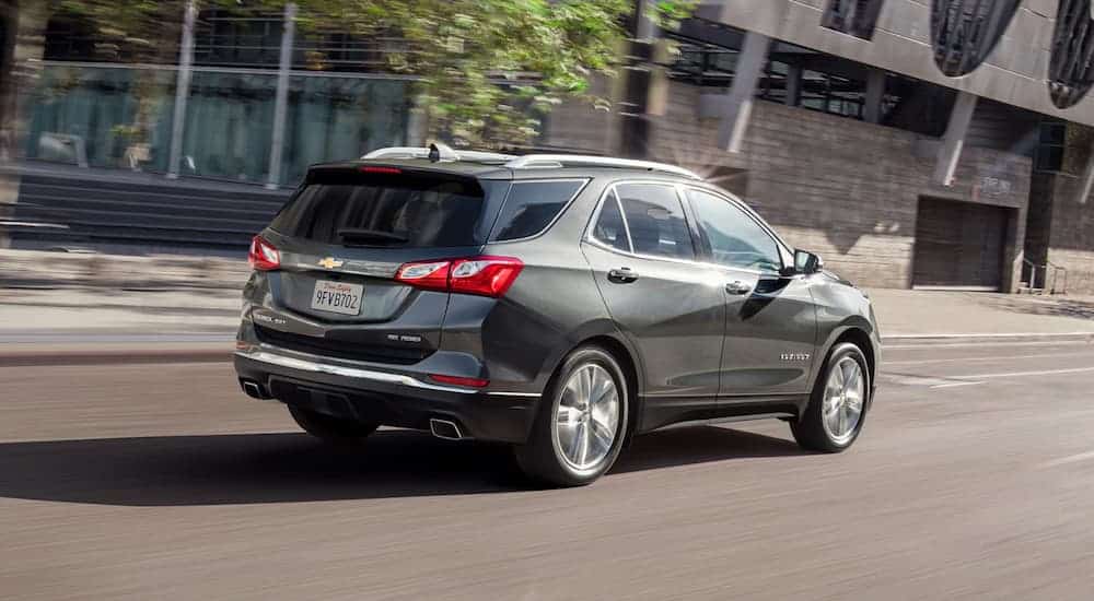 A grey 2020 Chevy Equinox is driving on a city street.