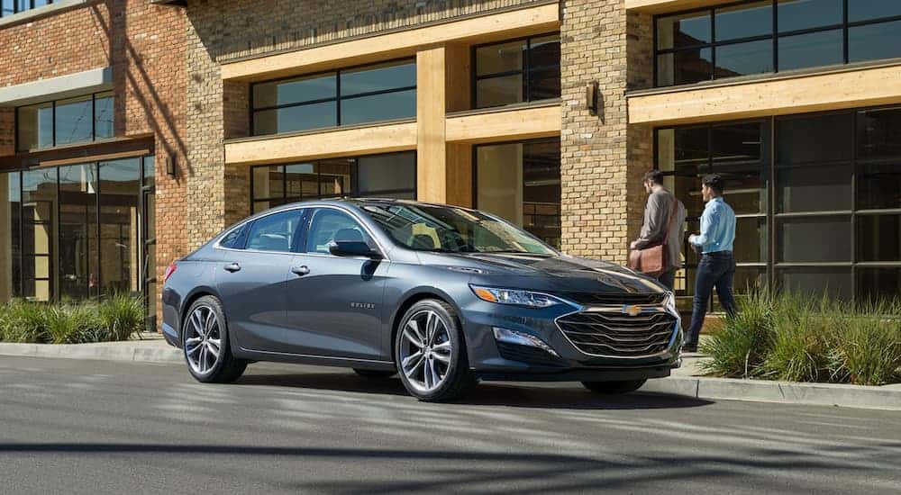 A grey 2020 Chevy Malibu is parked on a city street after leaving a Chevy dealer.