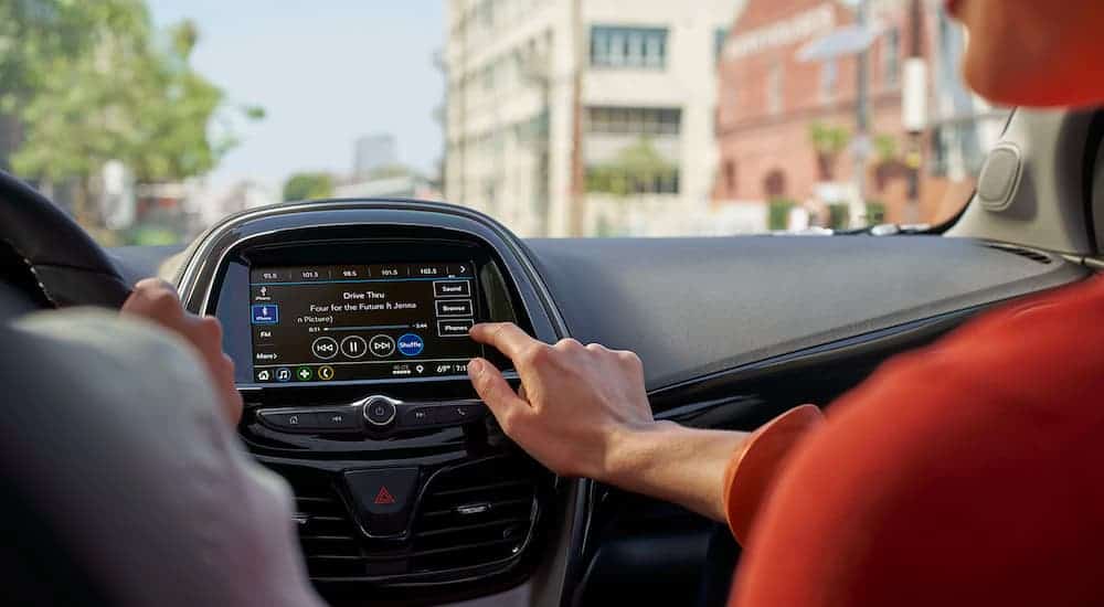 A close up is showing a woman using the infotainment system on a 2021 Chevy Spark.