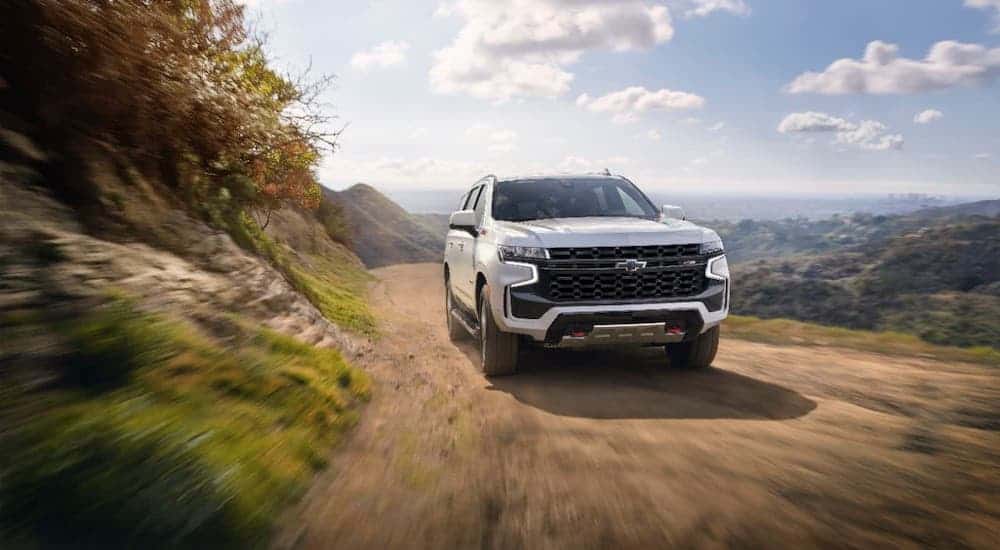 A white 2021 Chevy Tahoe Z71 is driving on a dirt road.