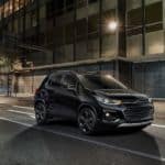 A black 2021 Chevy Trax is driving on a city street at night.