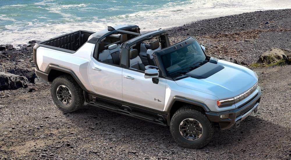 A popular electric vehicle, a 2021 GMC Hummer EV, is parked on the beach with the infinity roof open.